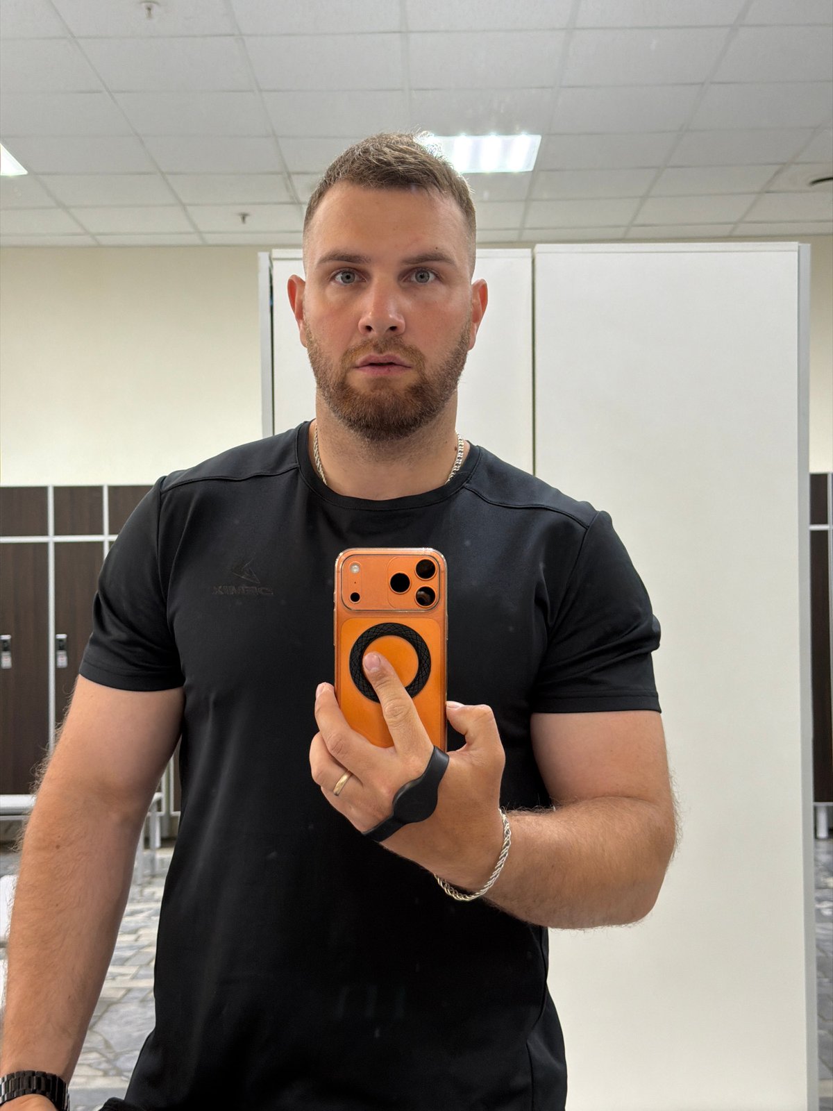 Man Takes Mirror Selfie with Orange Phone in Chaikovsky