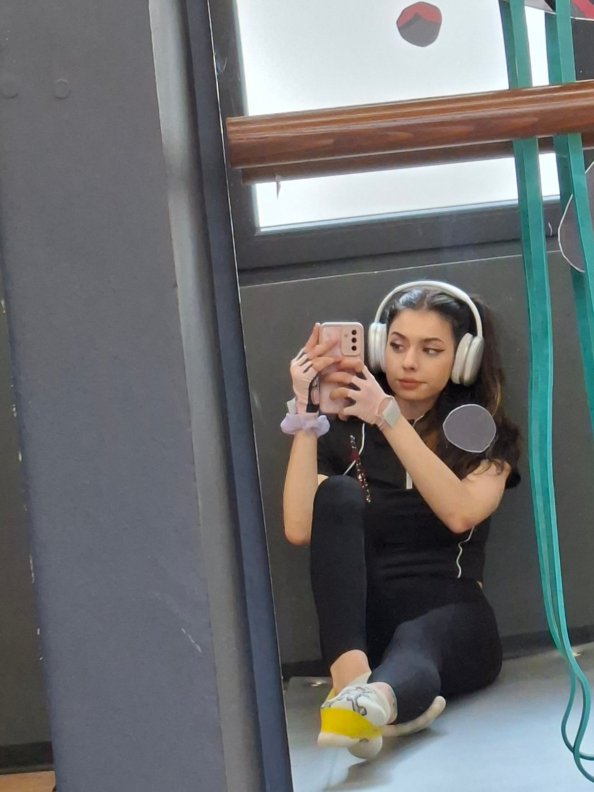 Woman takes mirror selfie wearing headphones in indoor setting
