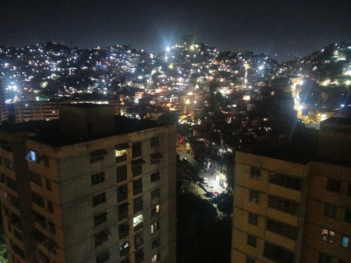 Nighttime observations document illuminated Caracas cityscape under moonlit sky