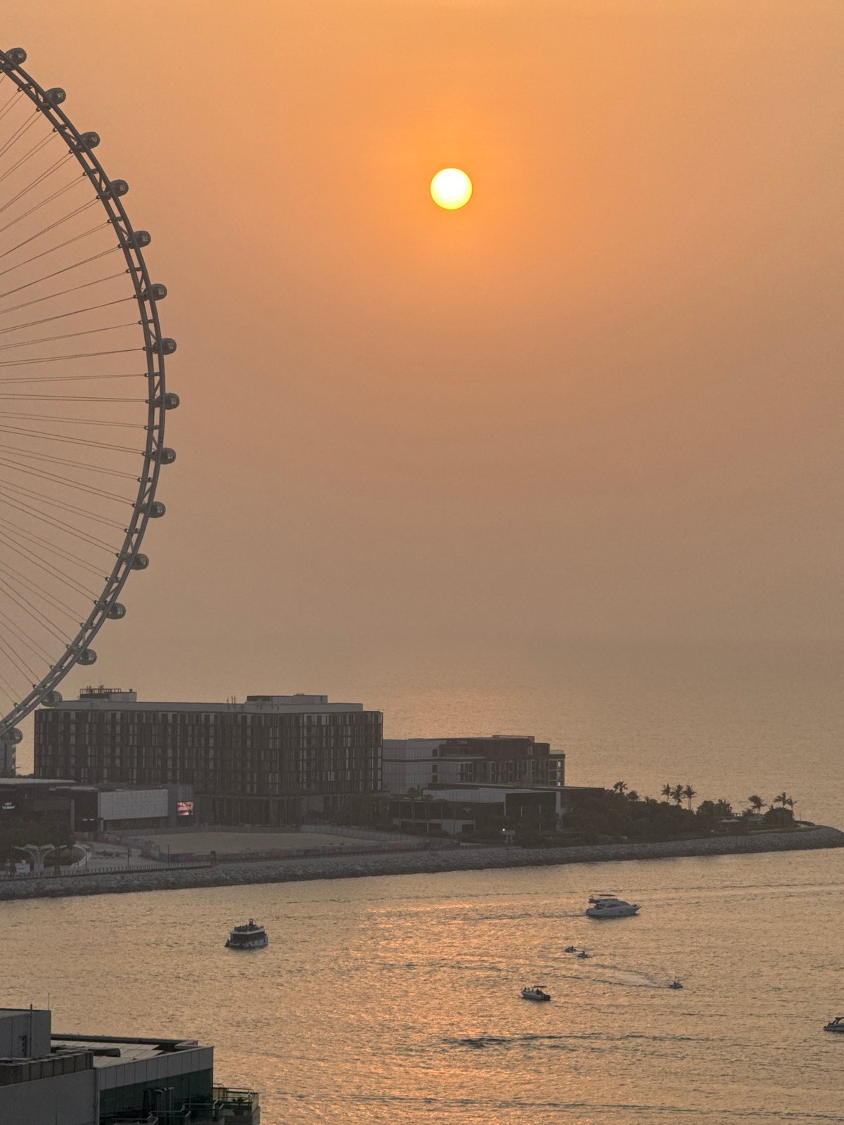 Hazy Gulf sunset with Ain Dubai from a Dubai high-rise