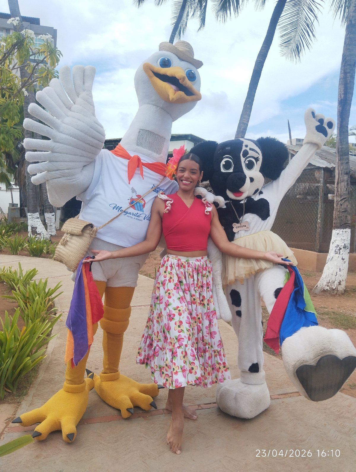 Woman poses with mascots in tropical outdoor setting
