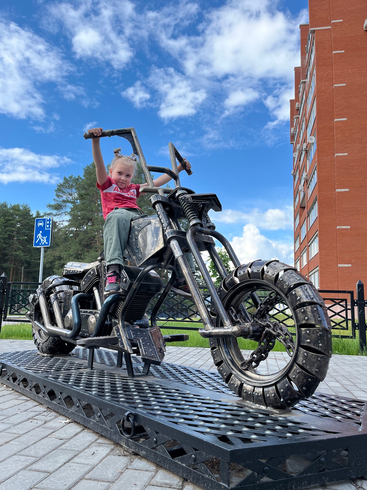 Child plays on metal motorcycle sculpture in Chaikovsky