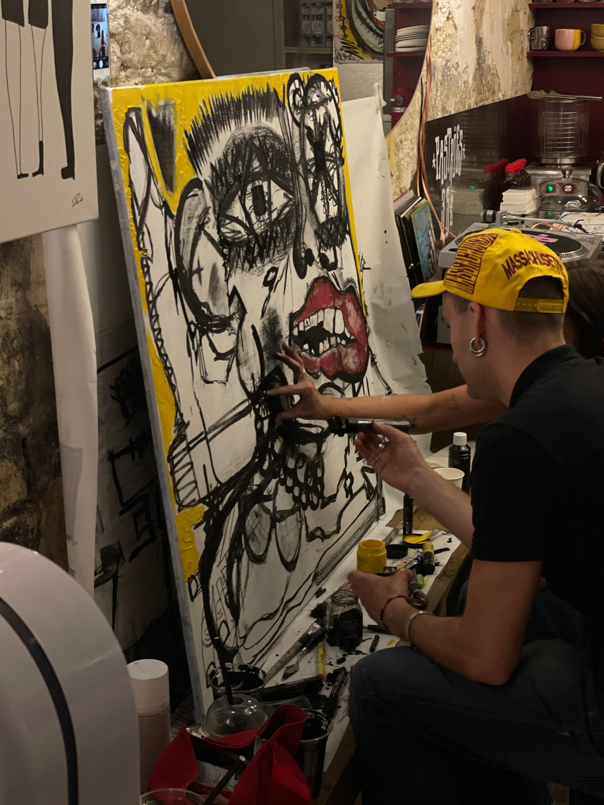 Artist creates black-yellow abstract painting on floor canvas in Paris