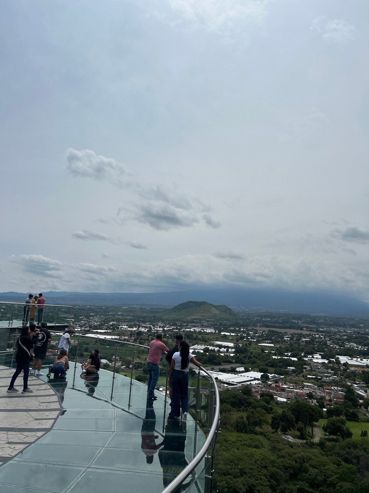 Glass observation deck overlooks Atlixco under cloudy skies