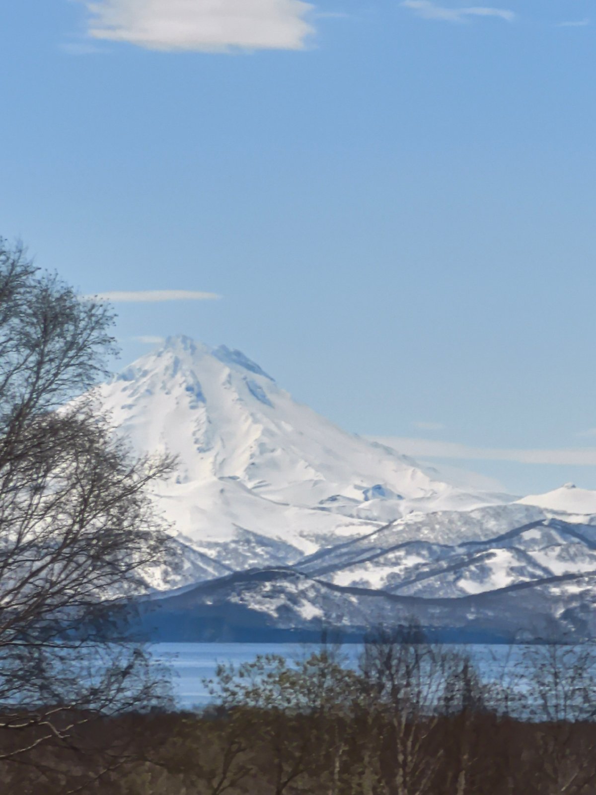 Snow-capped mountain observed through clouds in mountain landscape scene