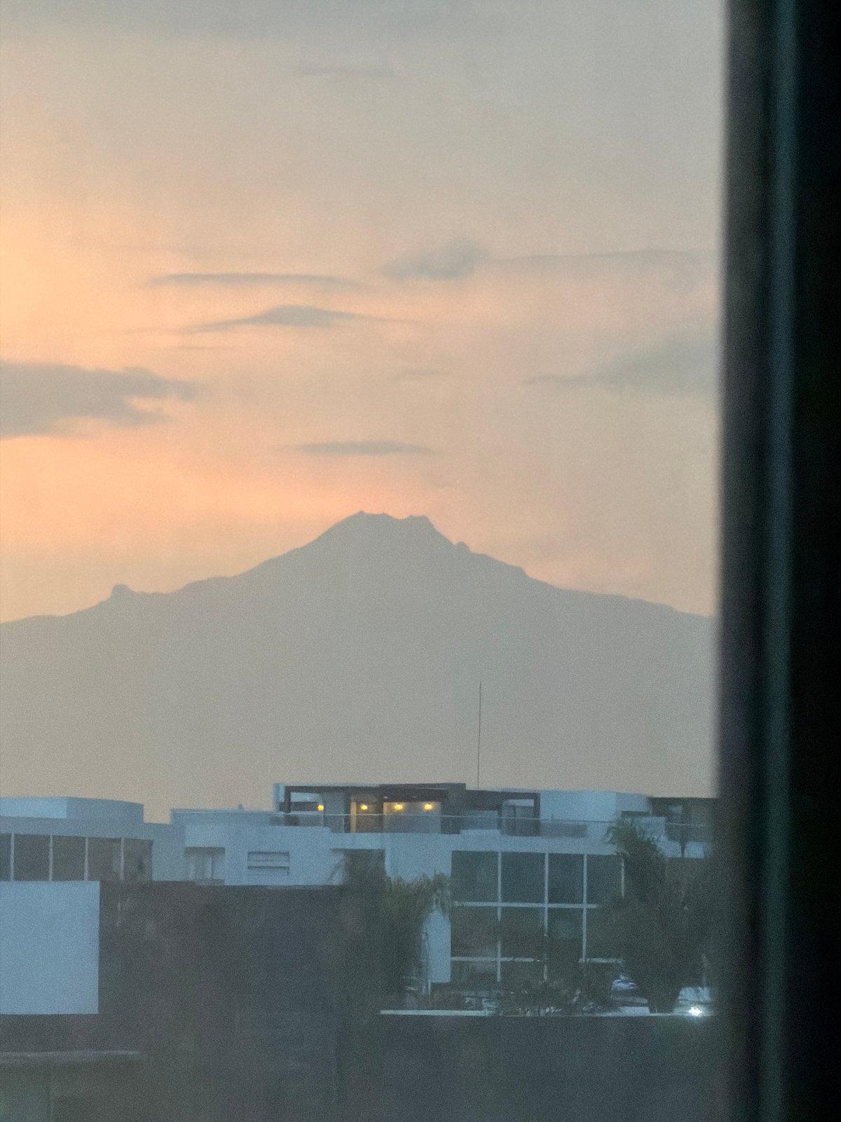 Window view captures San Andrés Cholula cityscape with mountains