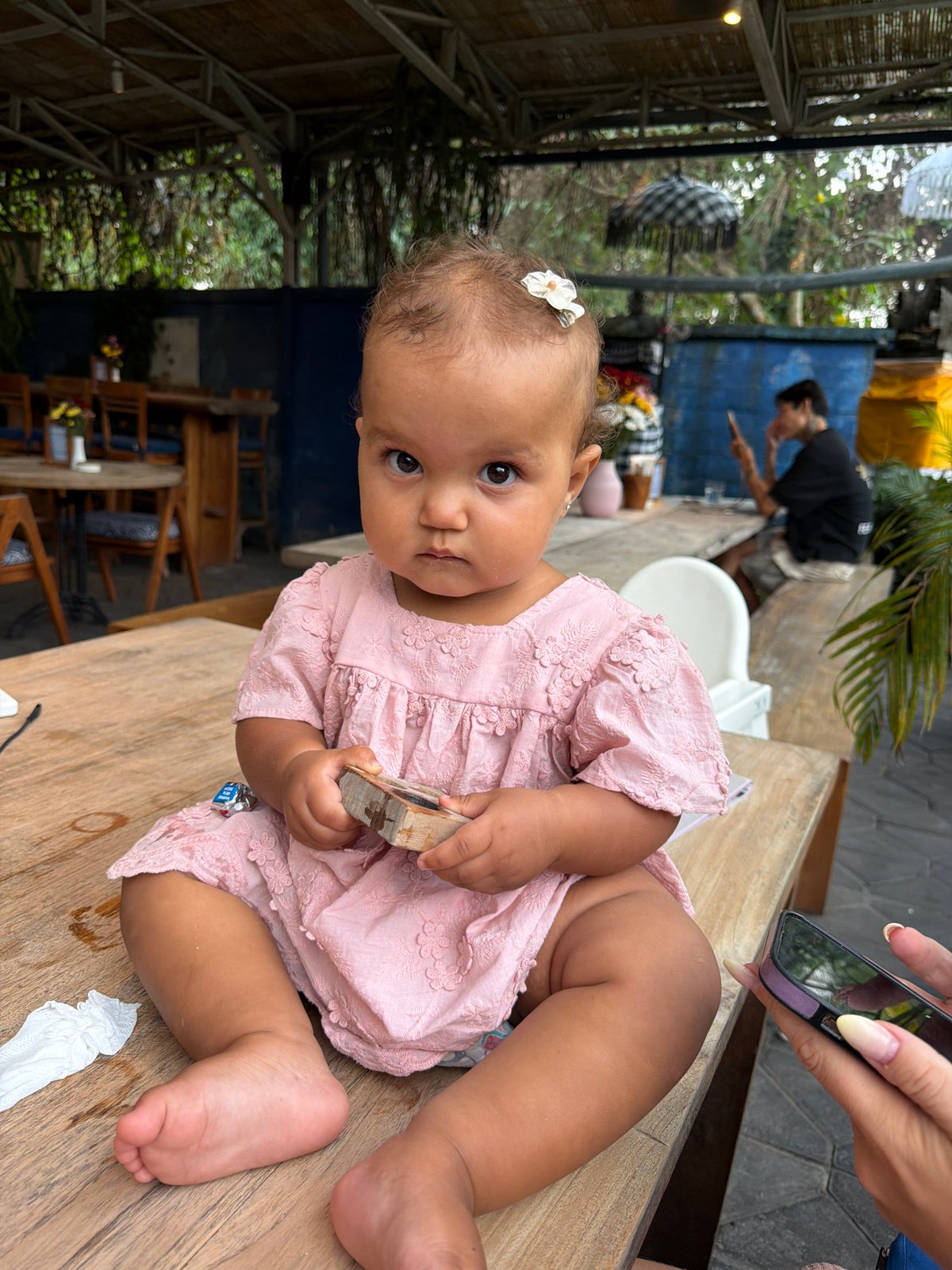 Toddler at an outdoor Ubud café, pink dress and flower clips