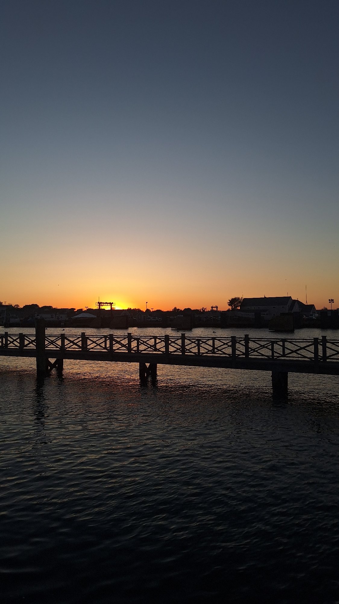 Sunset views across Nantucket harbor with pier and boats