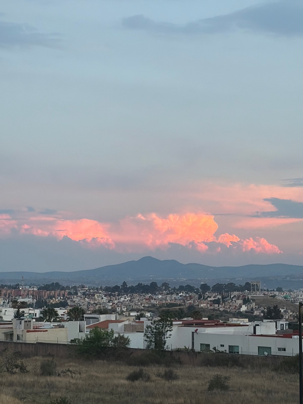 City skyline documented against mountain backdrop during evening hours