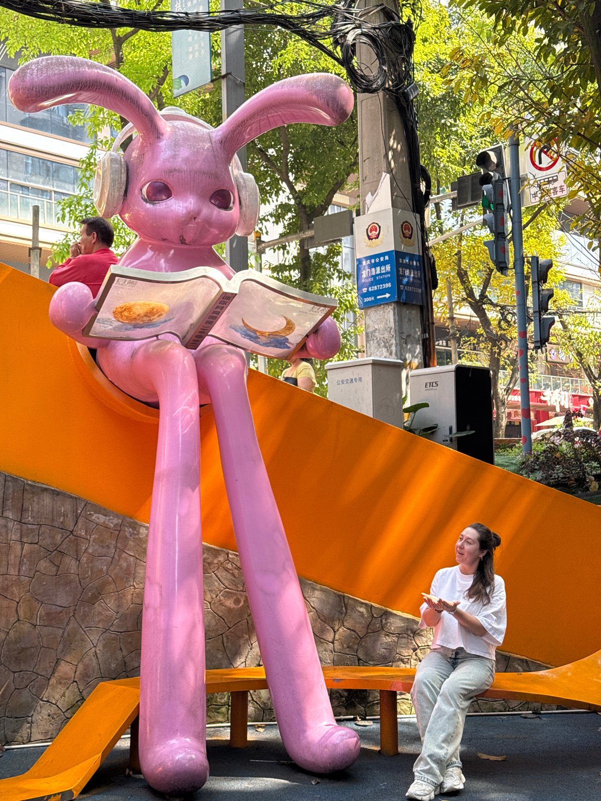 Woman interacts with pink rabbit sculpture in Chongqing