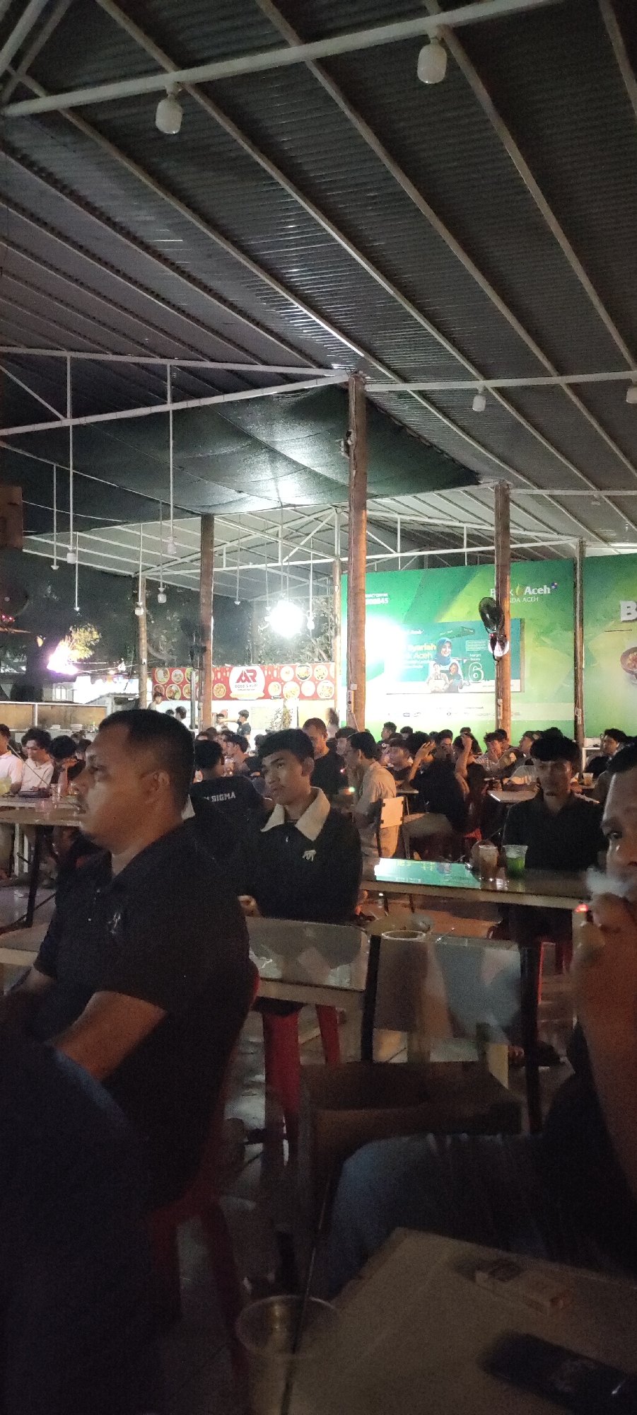 Banda Aceh cafe crowd watches a projected broadcast together