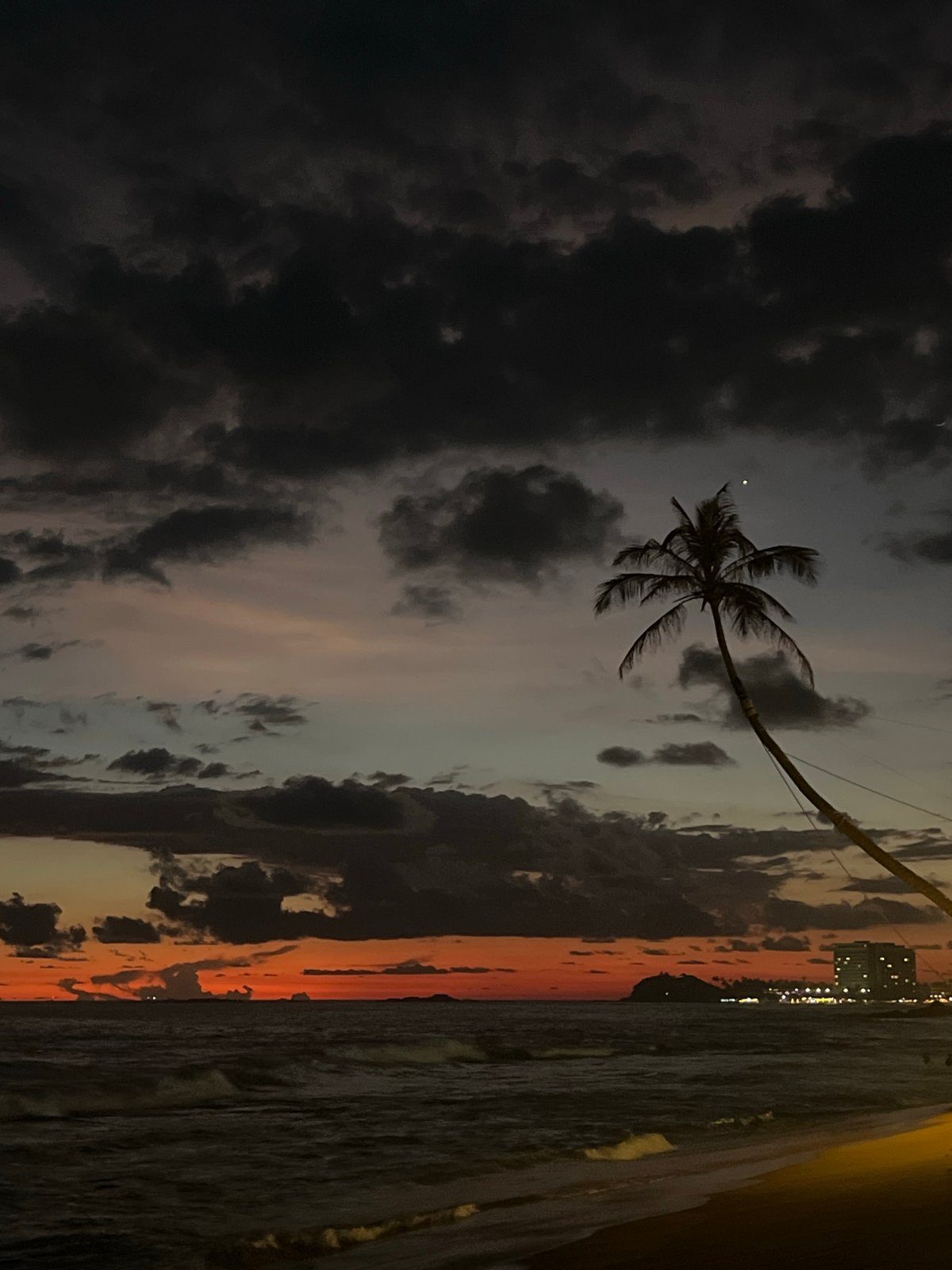 Dramatic sunset contrasts with storm clouds over Rumassala, Sri Lanka