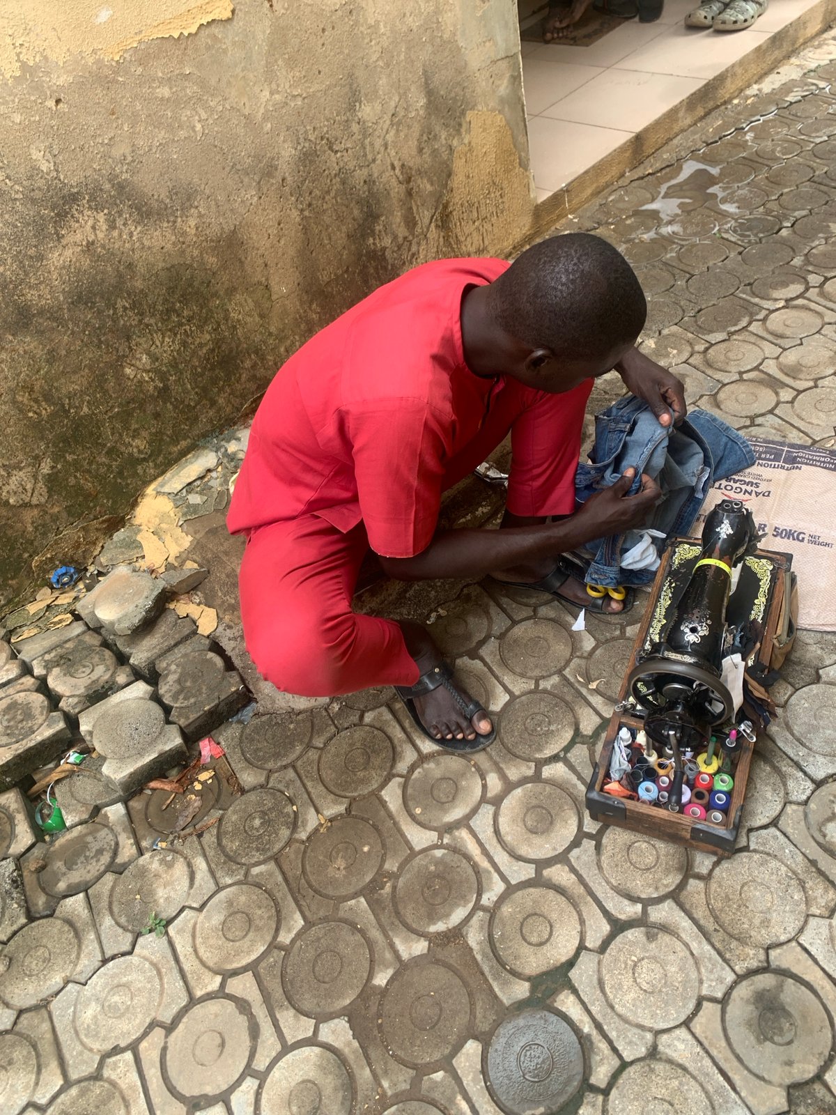 Street tailor operates vintage sewing machine outdoors in Abuja