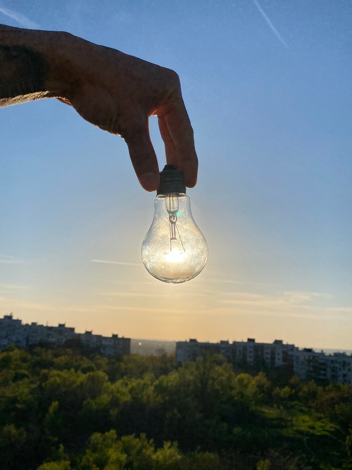 Hand holds lightbulb capturing sunlight in Pleven, Bulgaria