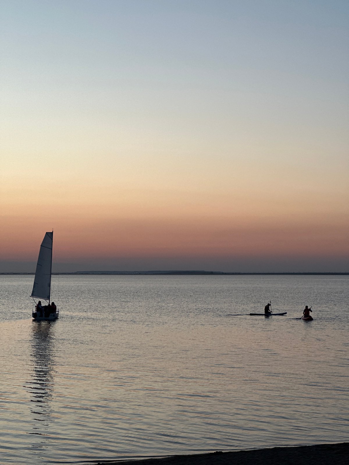 Sailboats and paddleboards on a Kazakh lake at dusk