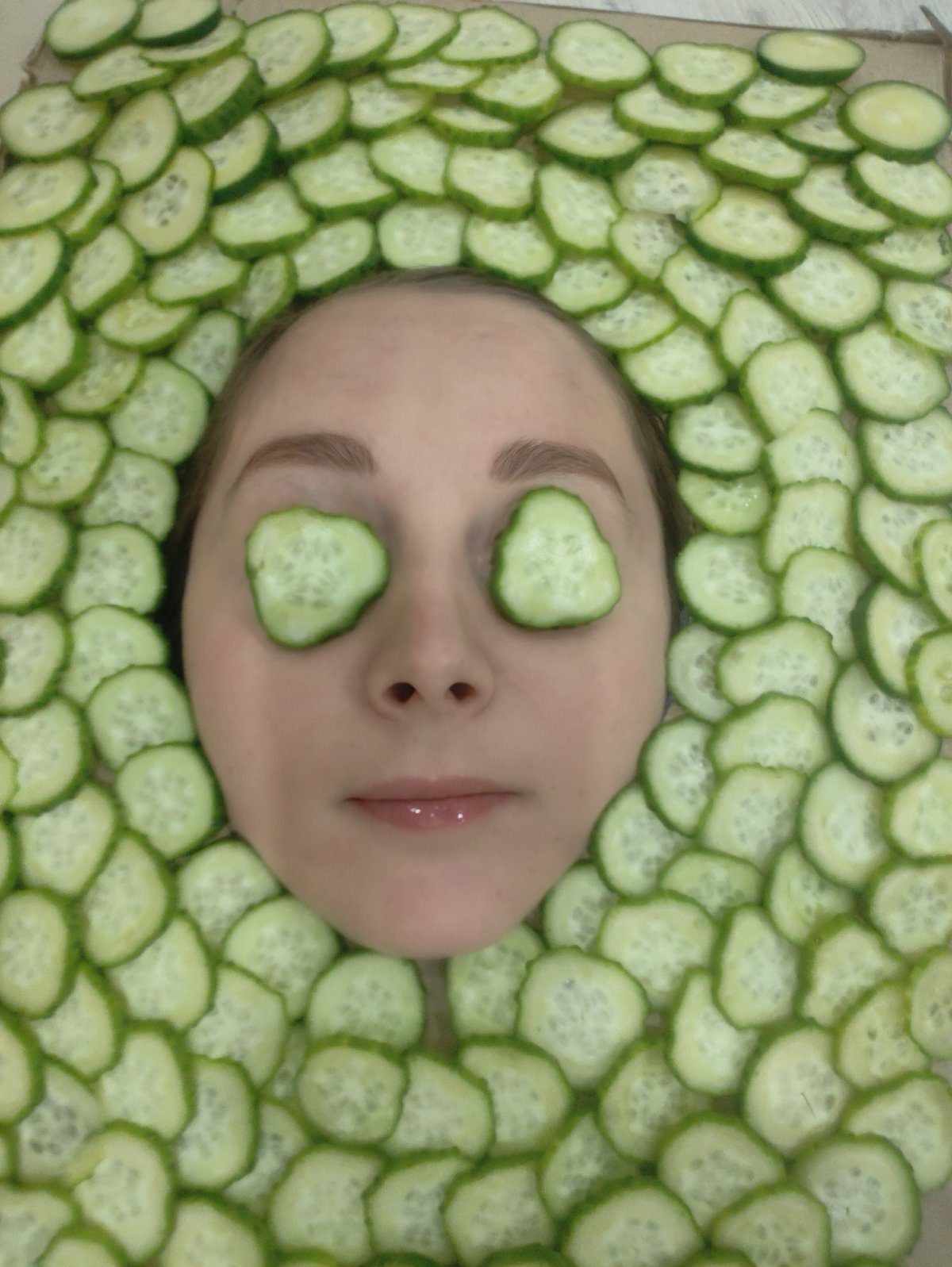 Woman receives cucumber facial treatment during evening spa session