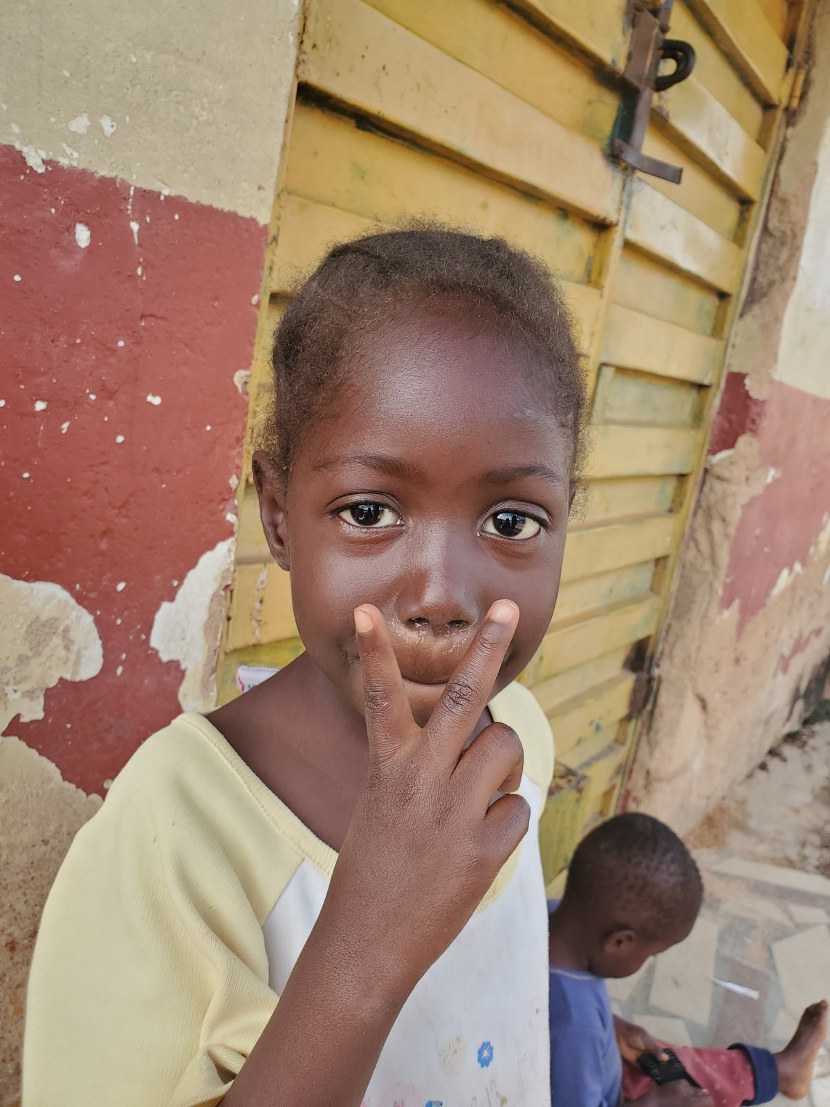 Kids and street life outside a yellow gate in Jos