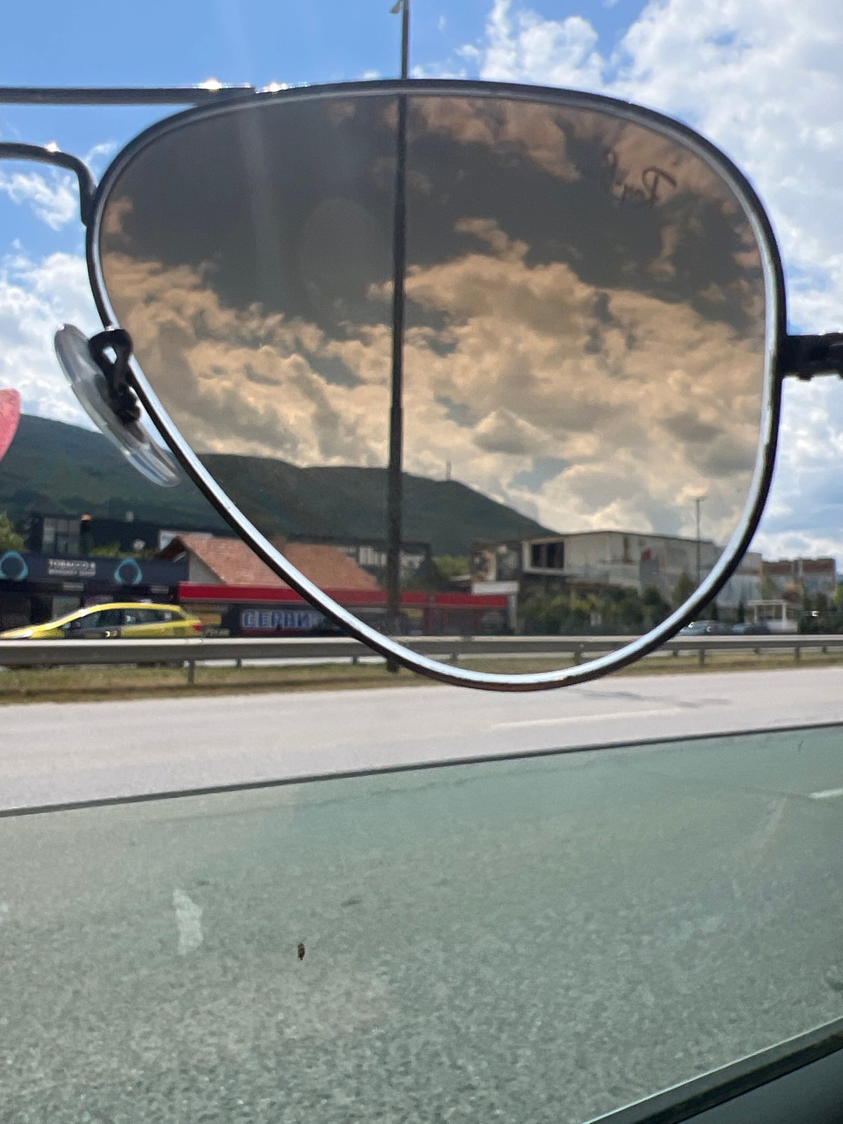 Sunglasses reflection frames a cloudy Sofia streetscape