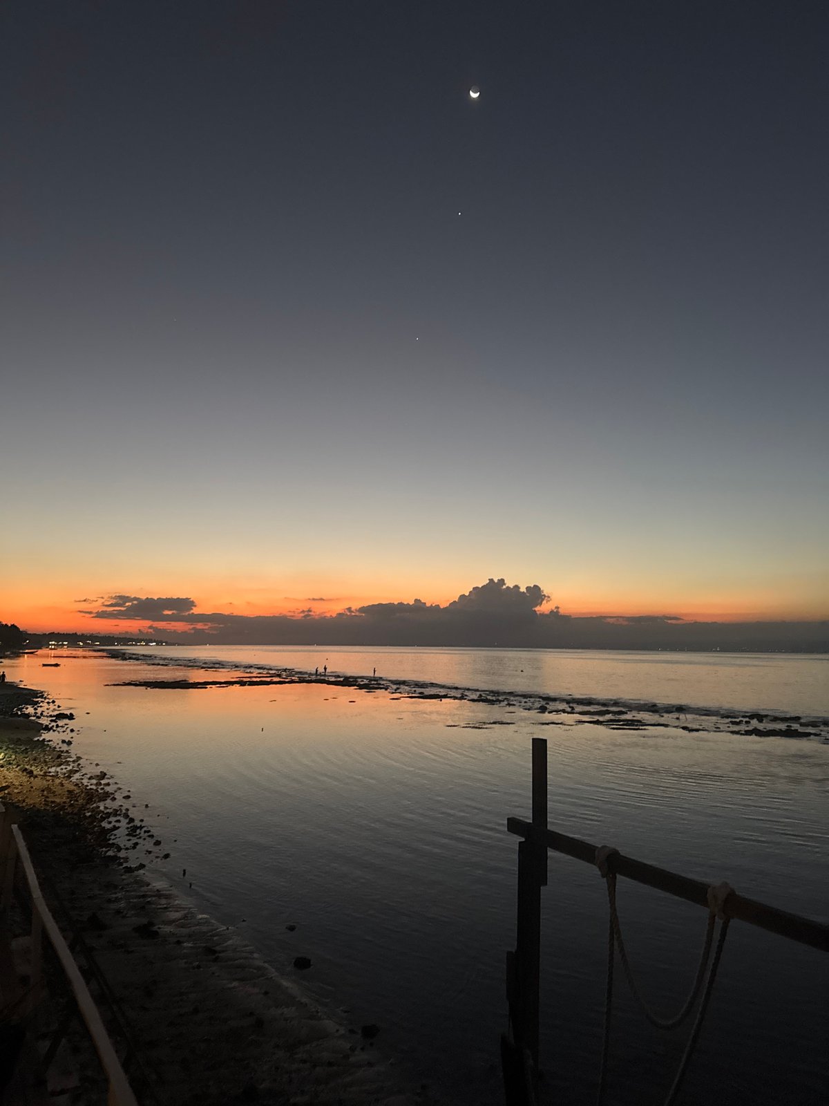 Crescent moon rises over Nusa Penida's glowing sunset waters
