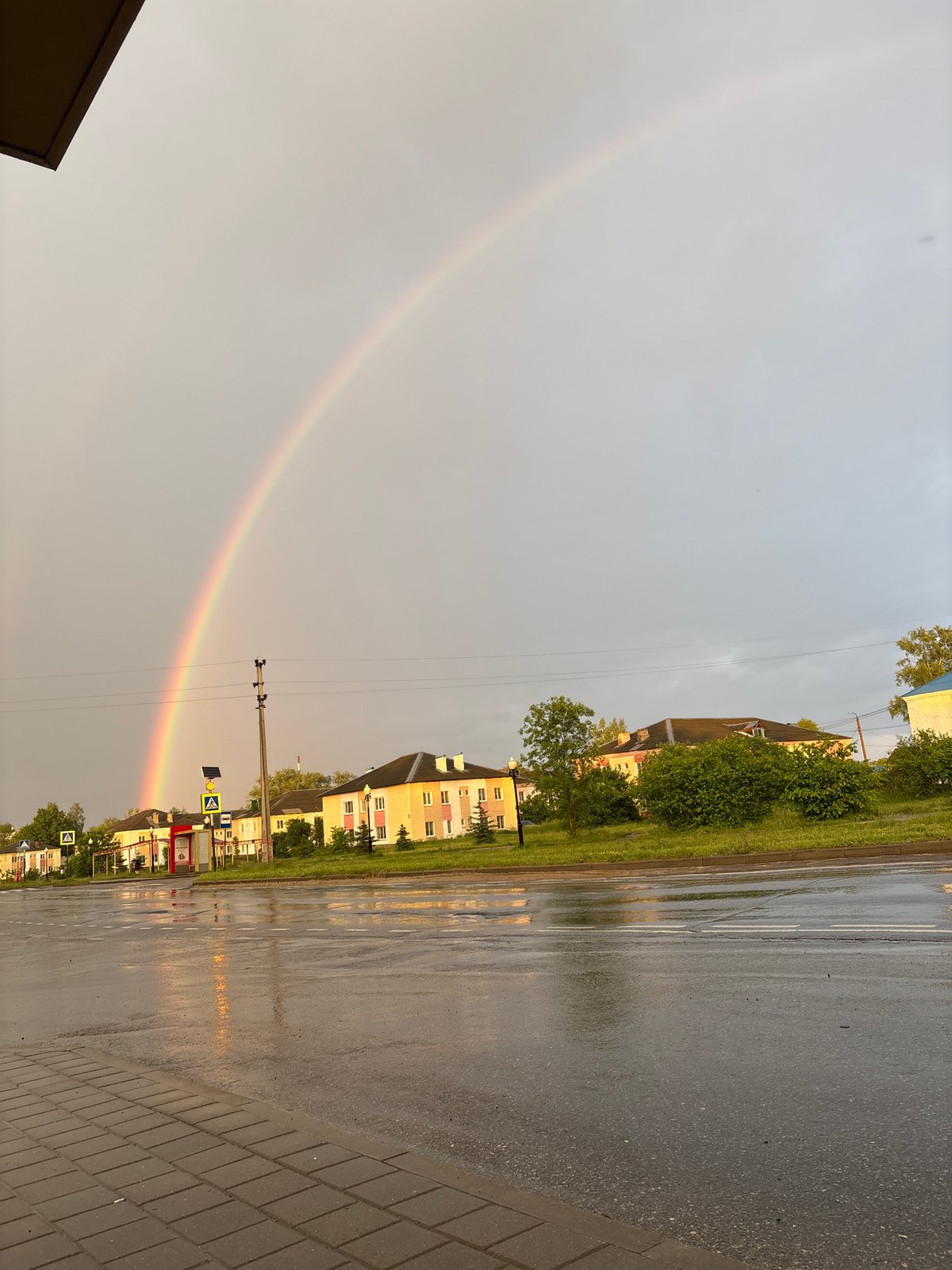 Rainbow appears over wet city streets after rainfall