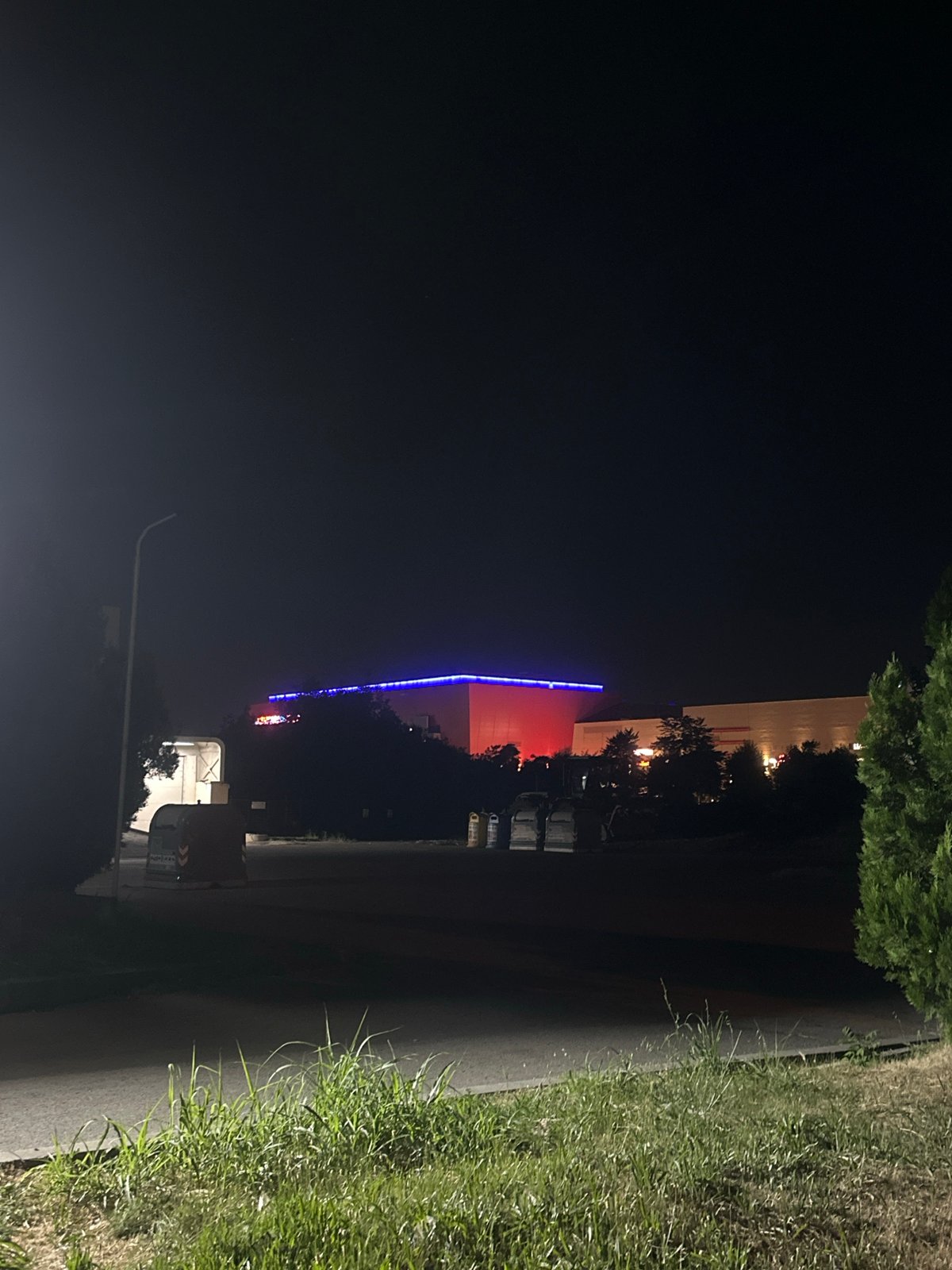 Tesla parked at night near neon-lit shops in Ruse, Bulgaria