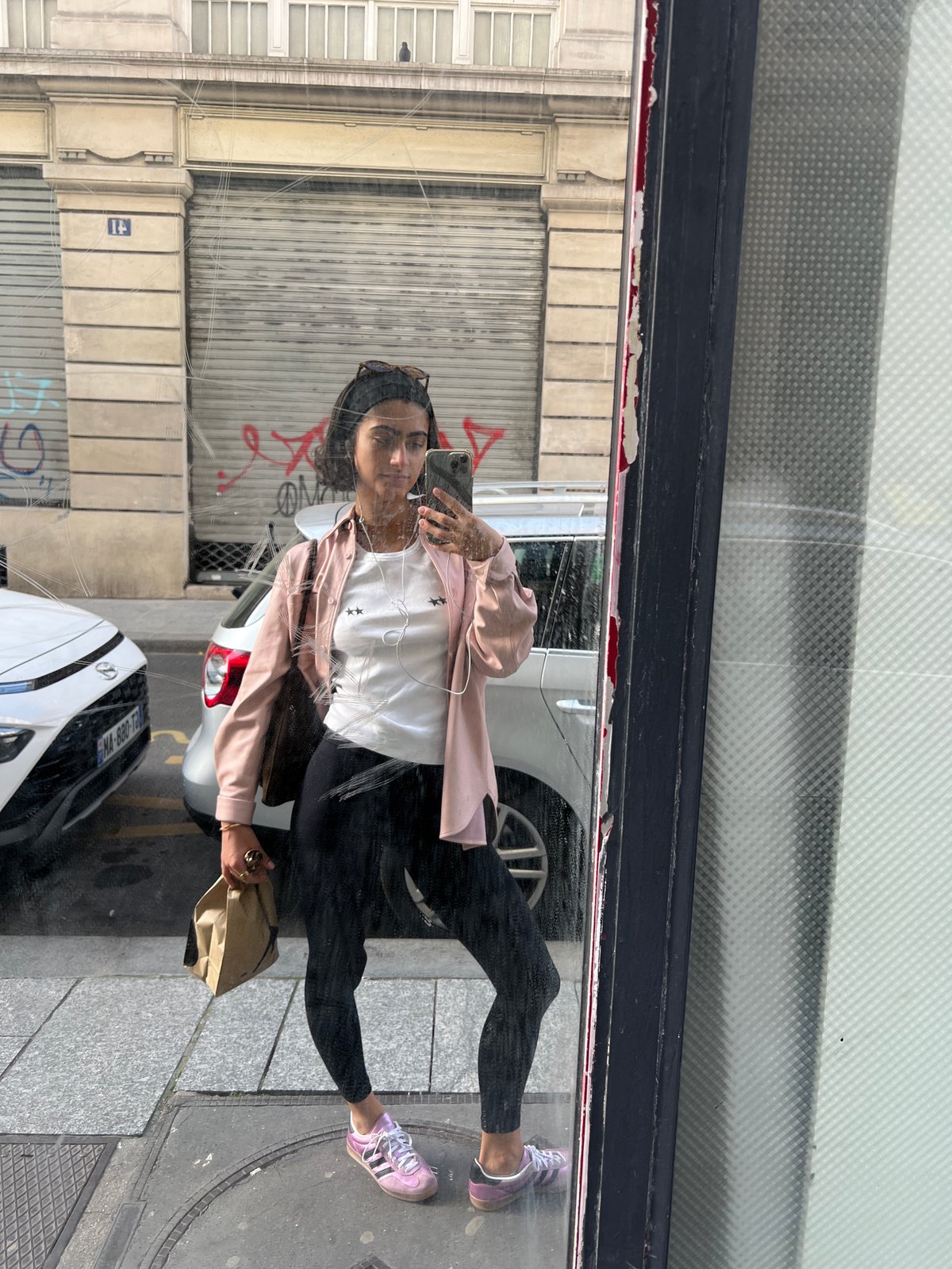 Woman captures selfie in Paris shop window reflection