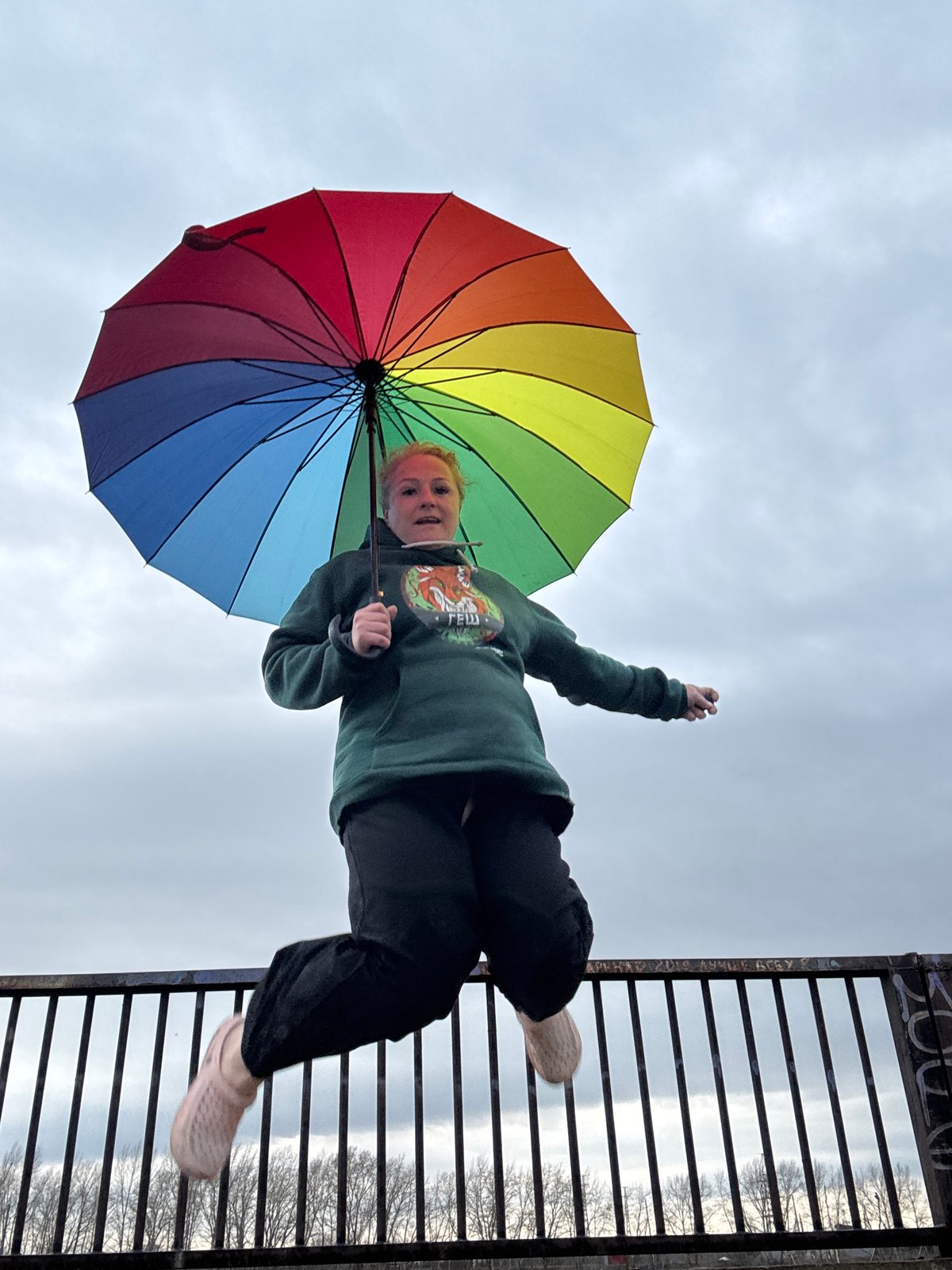 Woman with rainbow umbrella photographed by water in Chaikovsky