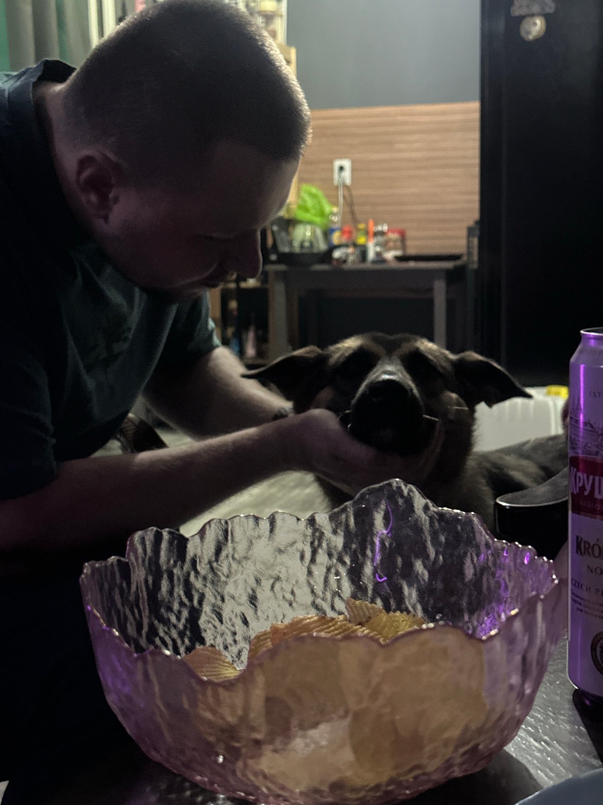 Man smokes hookah with dog in purple-lit Blagoveshchensk room