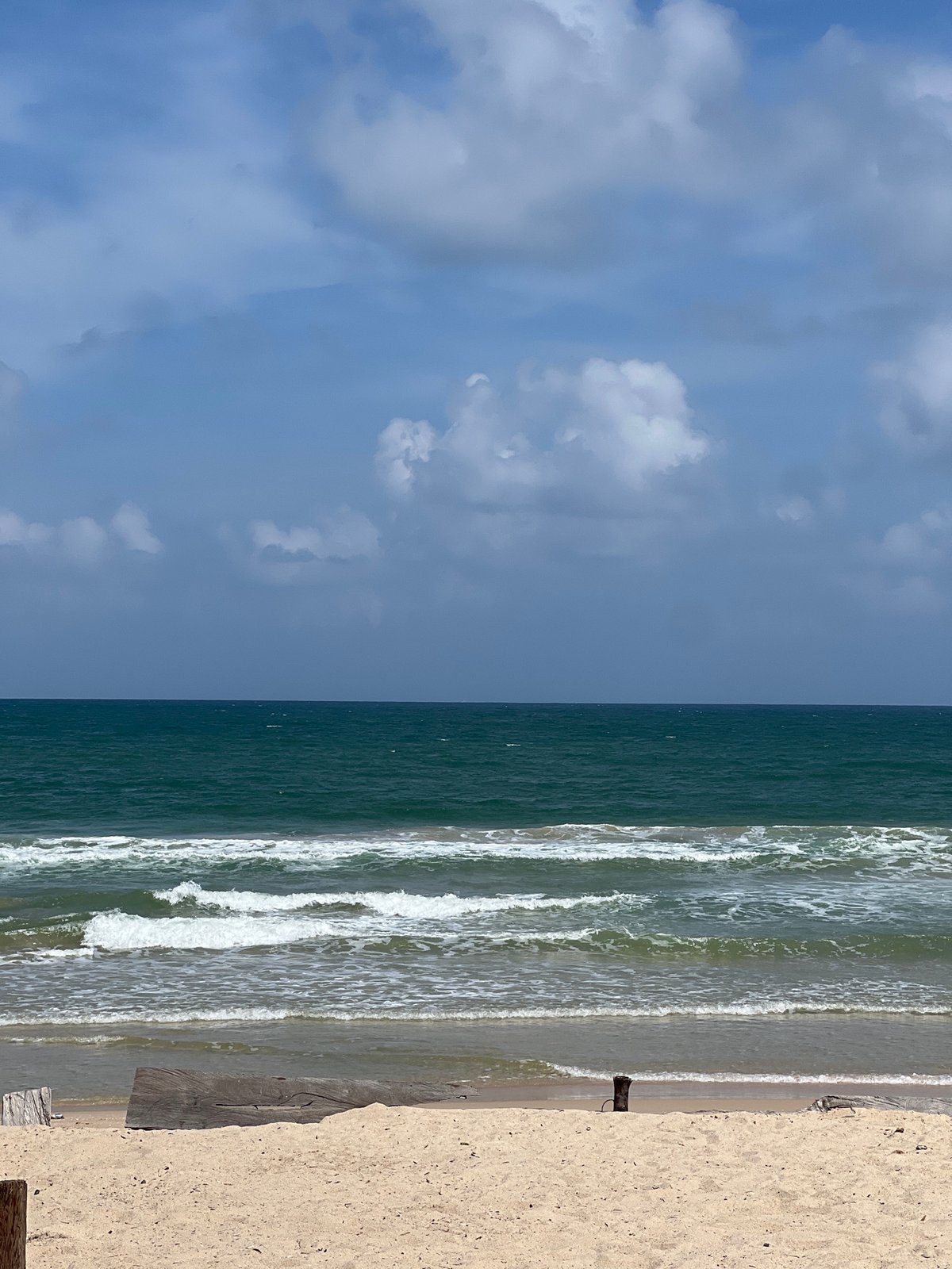 Surfers and beachgoers on Choeng Thale's shores, cloudy summer morning