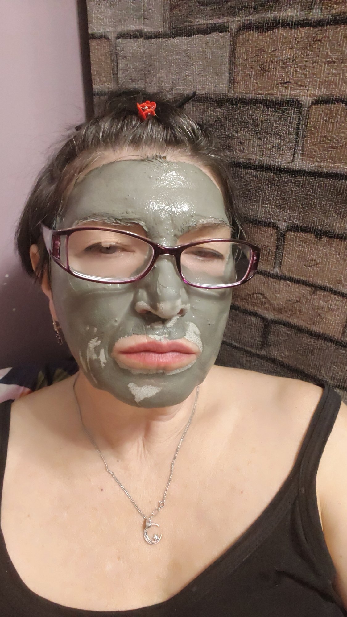 Woman applies clay facial mask during skincare routine in Krasnoyarsk