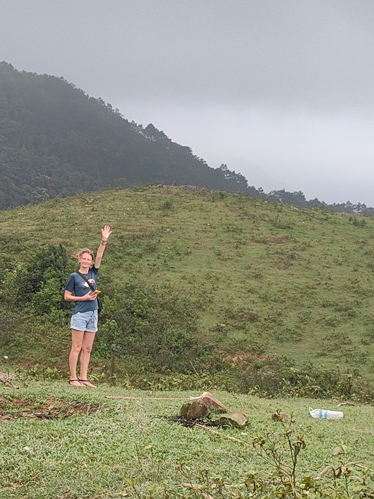 Woman waves near resting water buffalo in Vietnamese commune