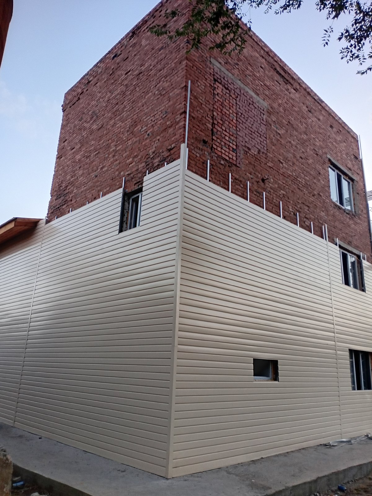 Brick building getting vinyl siding in Semey, Kazakhstan