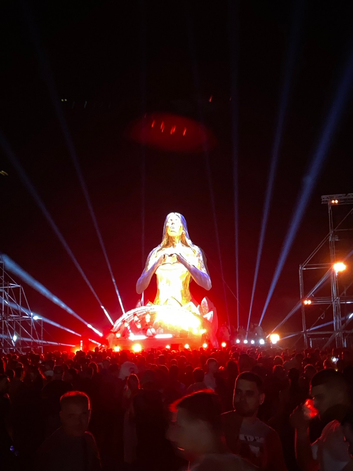 Crowds gather around glowing golden meditation statue at night festival