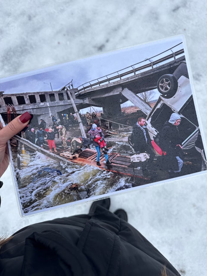 Person holds bridge destruction photo in snowy Irpin Ukraine