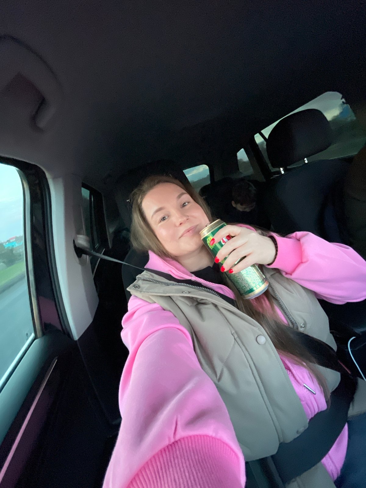 Woman drinks from can while traveling in car