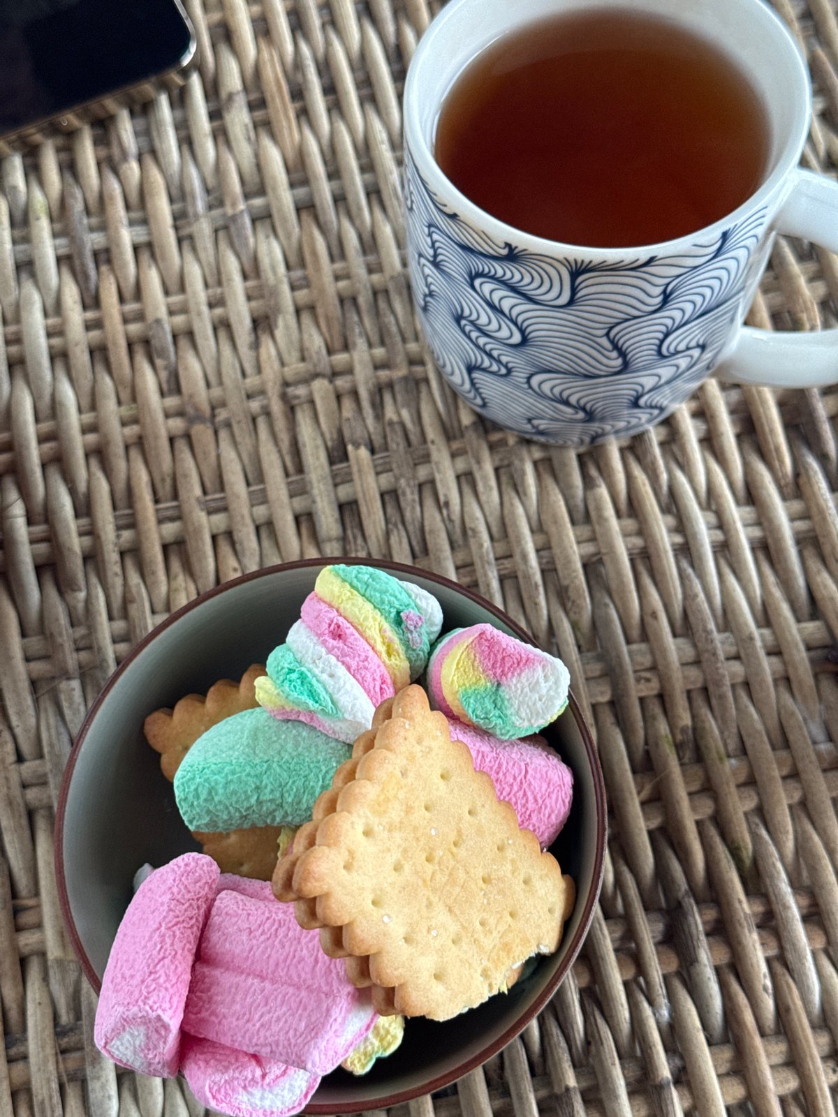 Tea and snacks on a woven tray, rocky Sri Lankan coastline nearby