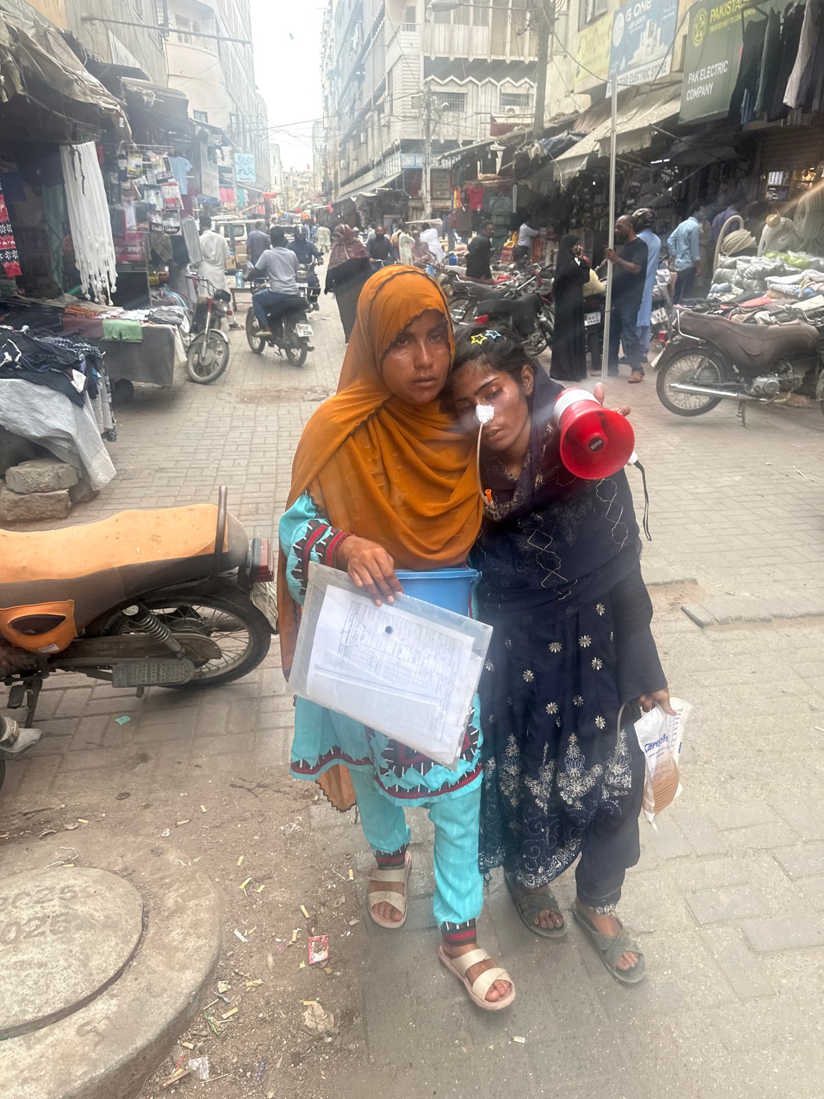 Two people in apparent distress on a Karachi street