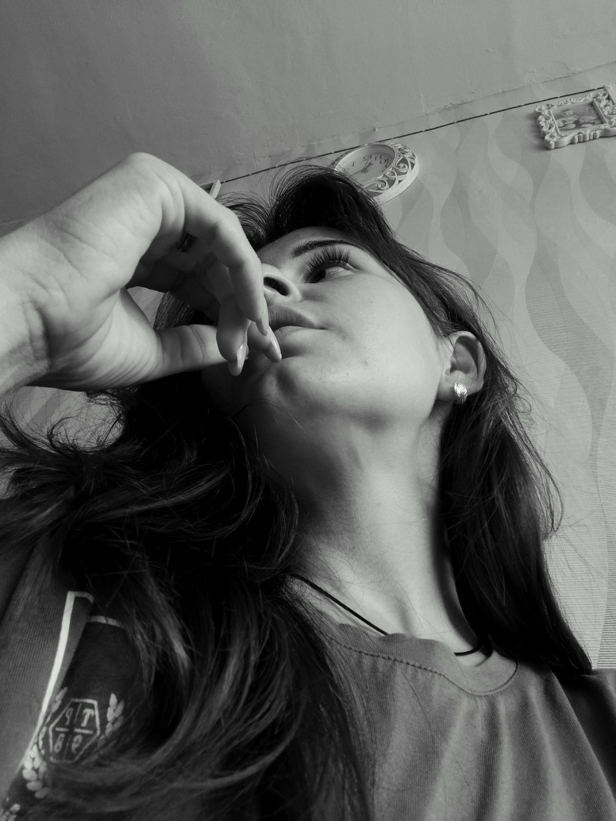 Black and white low-angle portrait, hand near lips, looking up