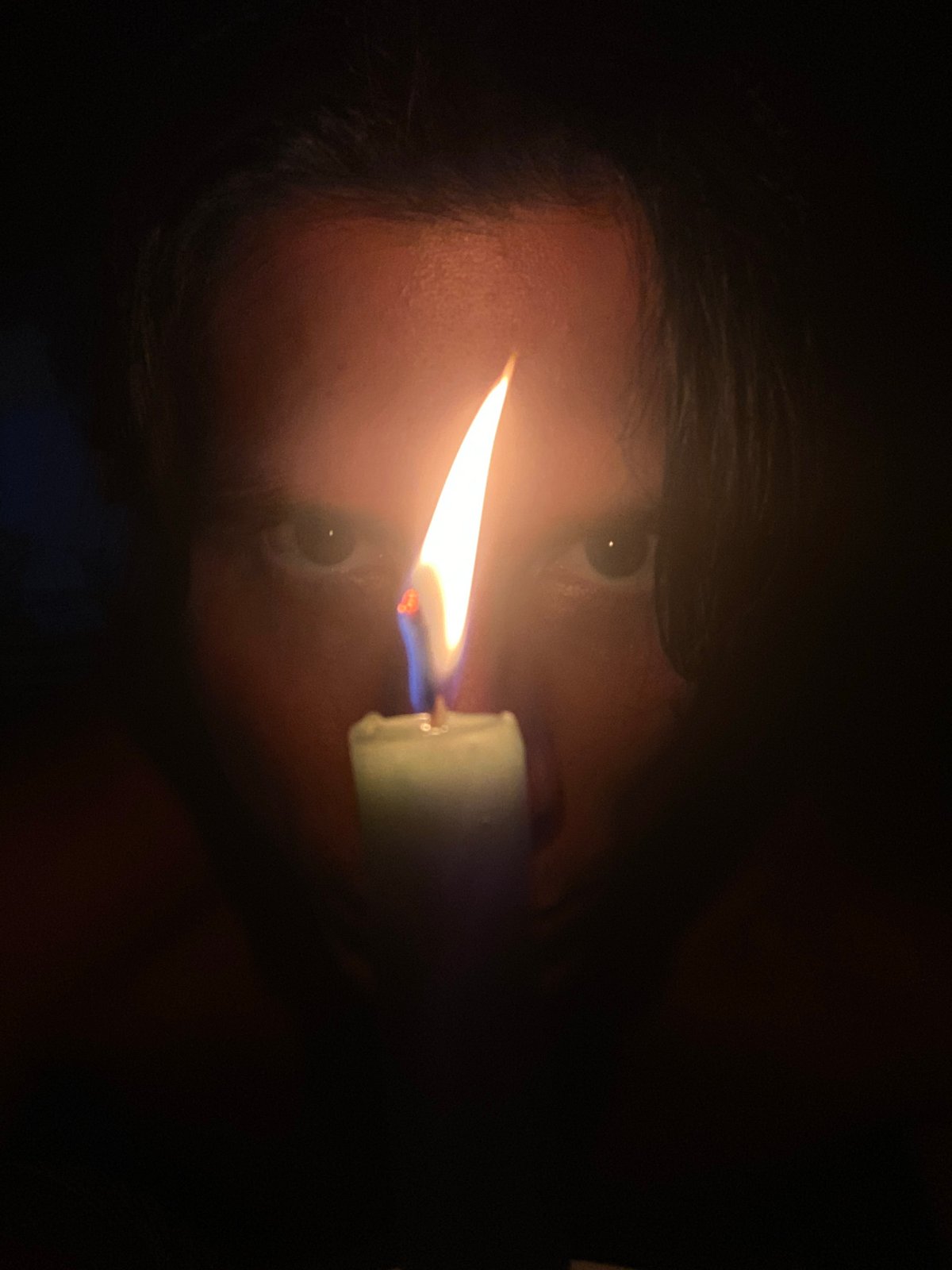 Person holds green candle in darkness in Venezuelan village