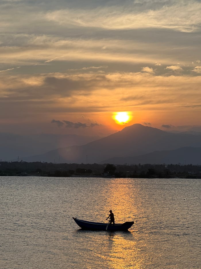 Sunset fishing boats and helmet-wearing individual documented in coastal Vietnam