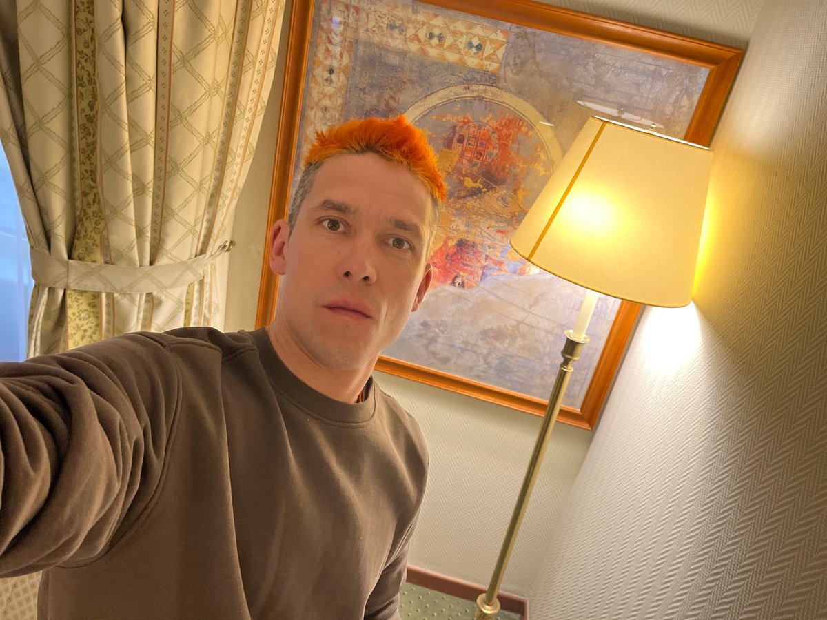 Orange-haired man photographed indoors in Moscow residential setting