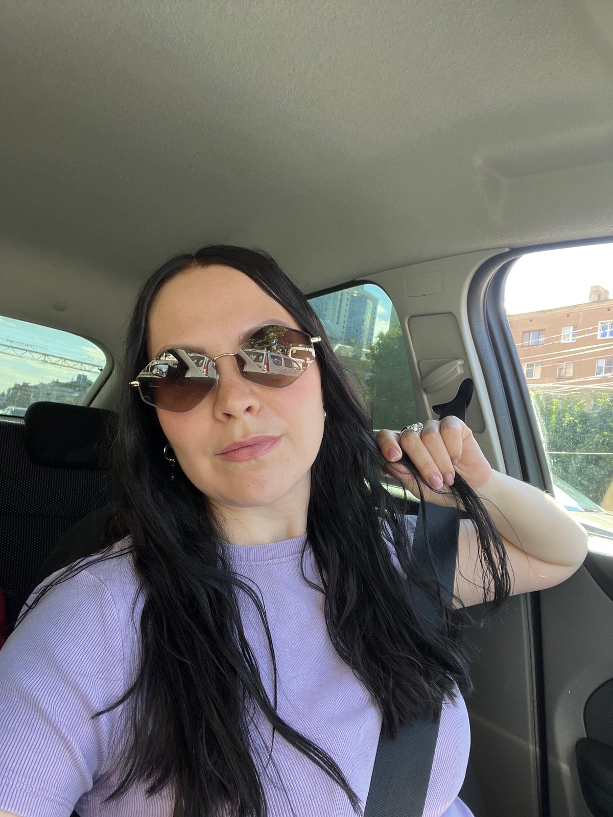 In-car selfie with reflective sunglasses, Voronezh streets in the background.