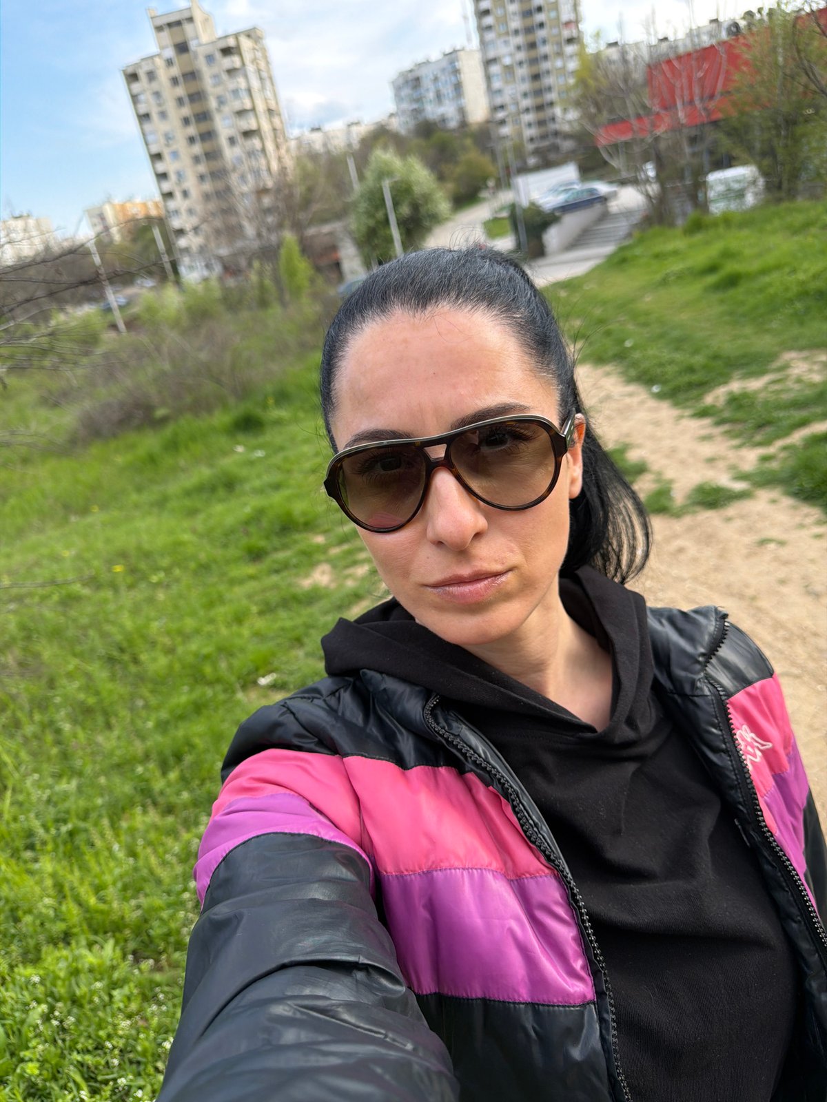 Woman takes selfies on Pleven street wearing colorful jacket