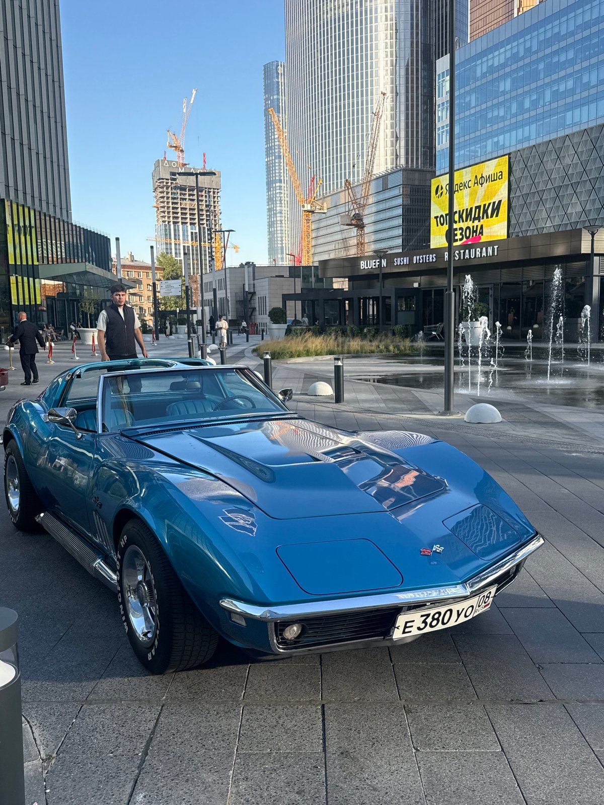 Classic blue Corvette Stingray parked outside modern Khimki building