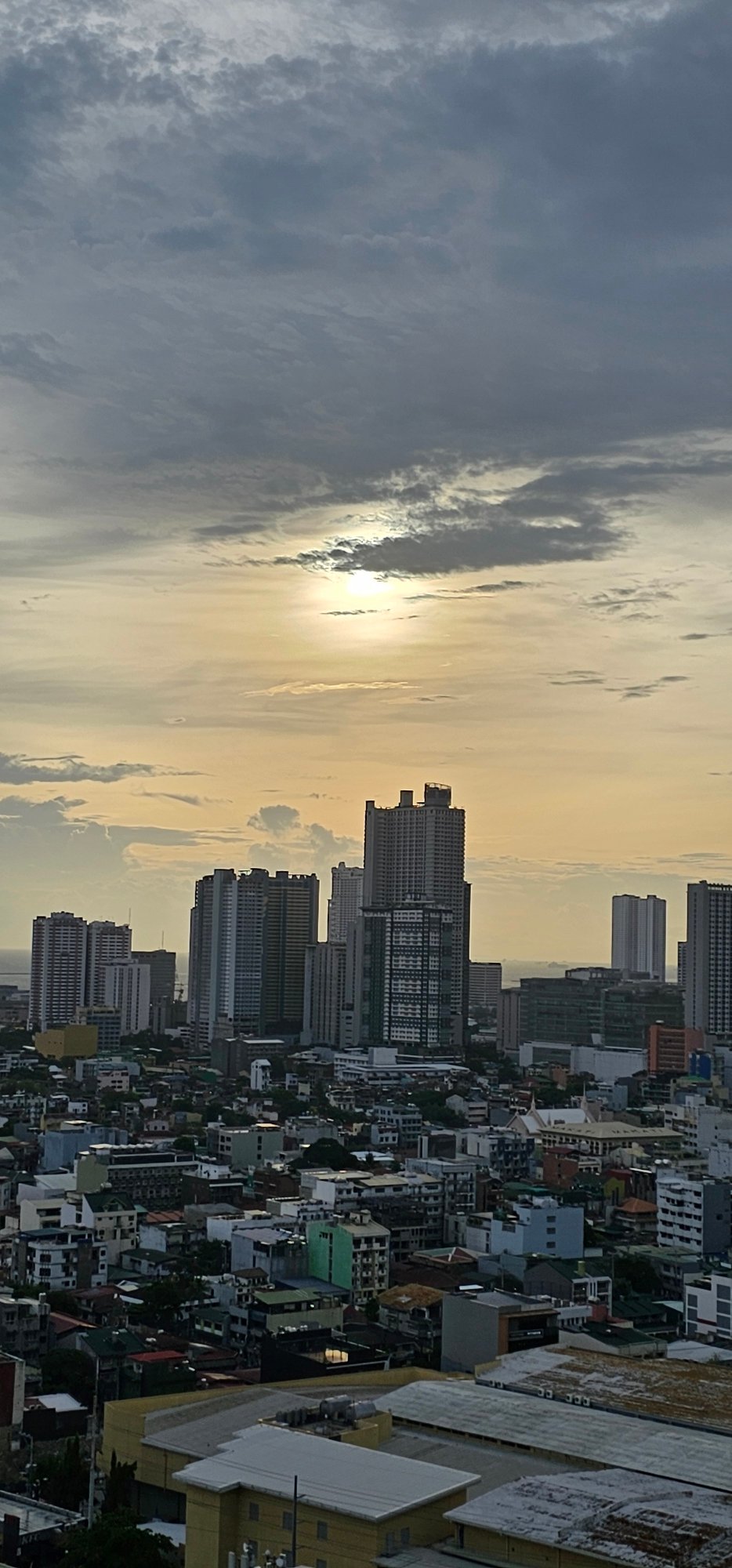Makati skyline glows at dusk as a plane passes overhead