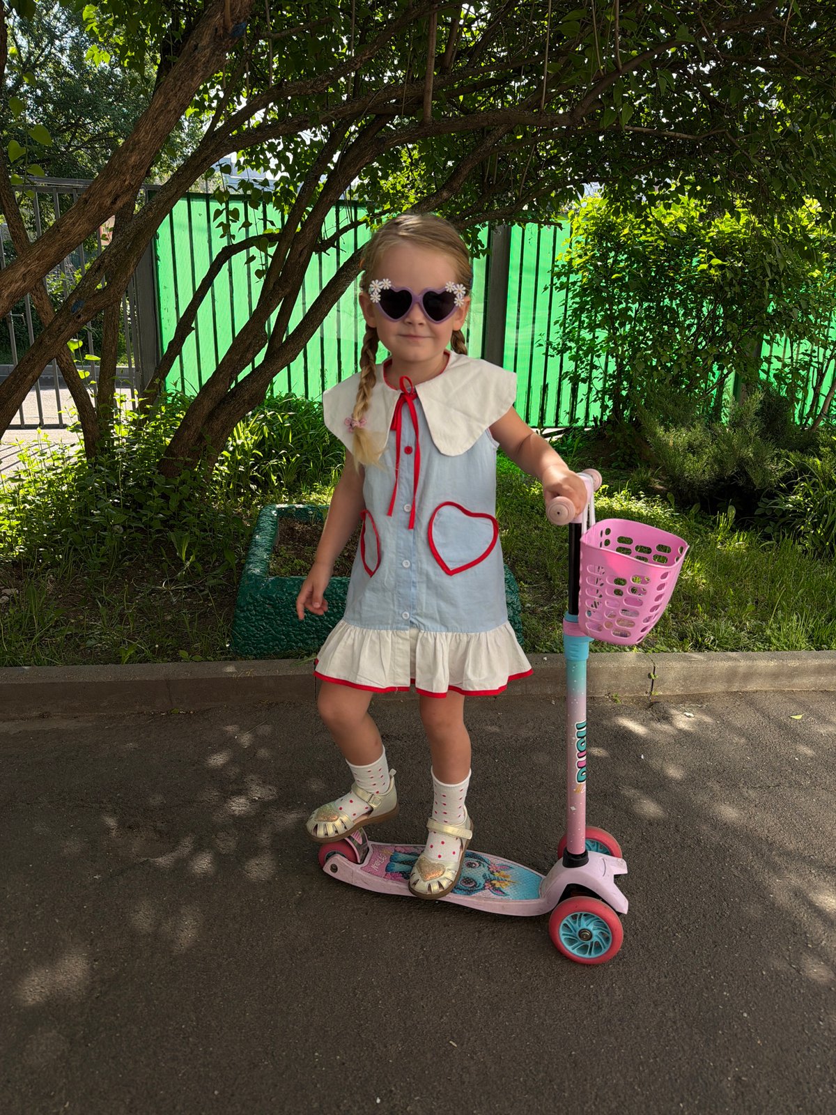 Girl with decorated sunglasses rides pink-basket scooter in Moscow