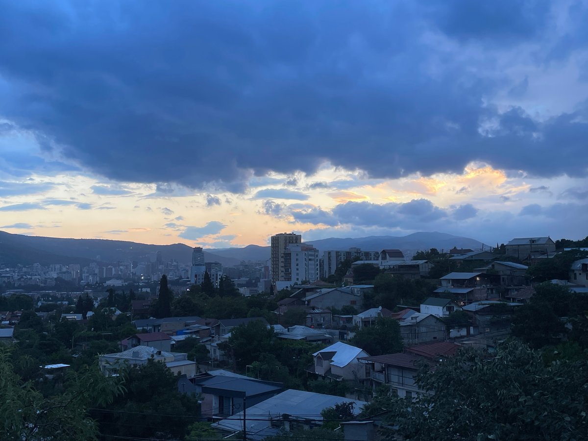 Tbilisi hillside at dusk, storm clouds rolling in