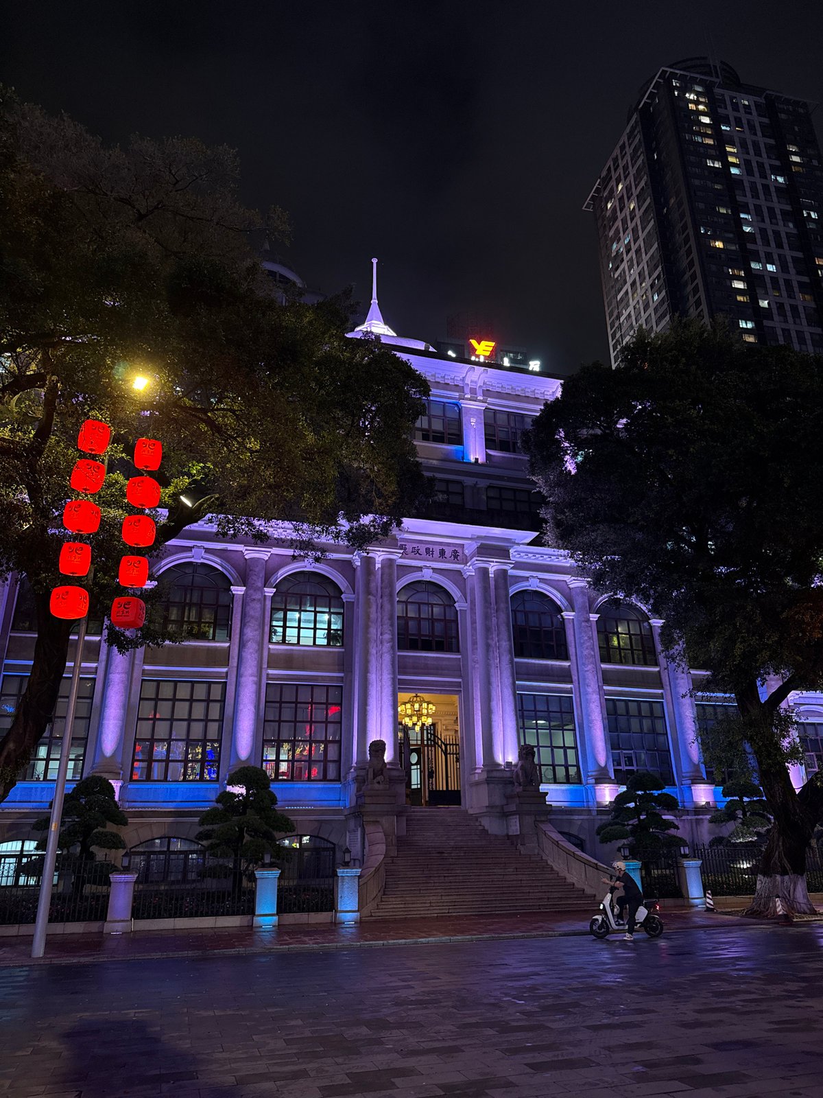 Woman walks illuminated street in Yuexiu District at night