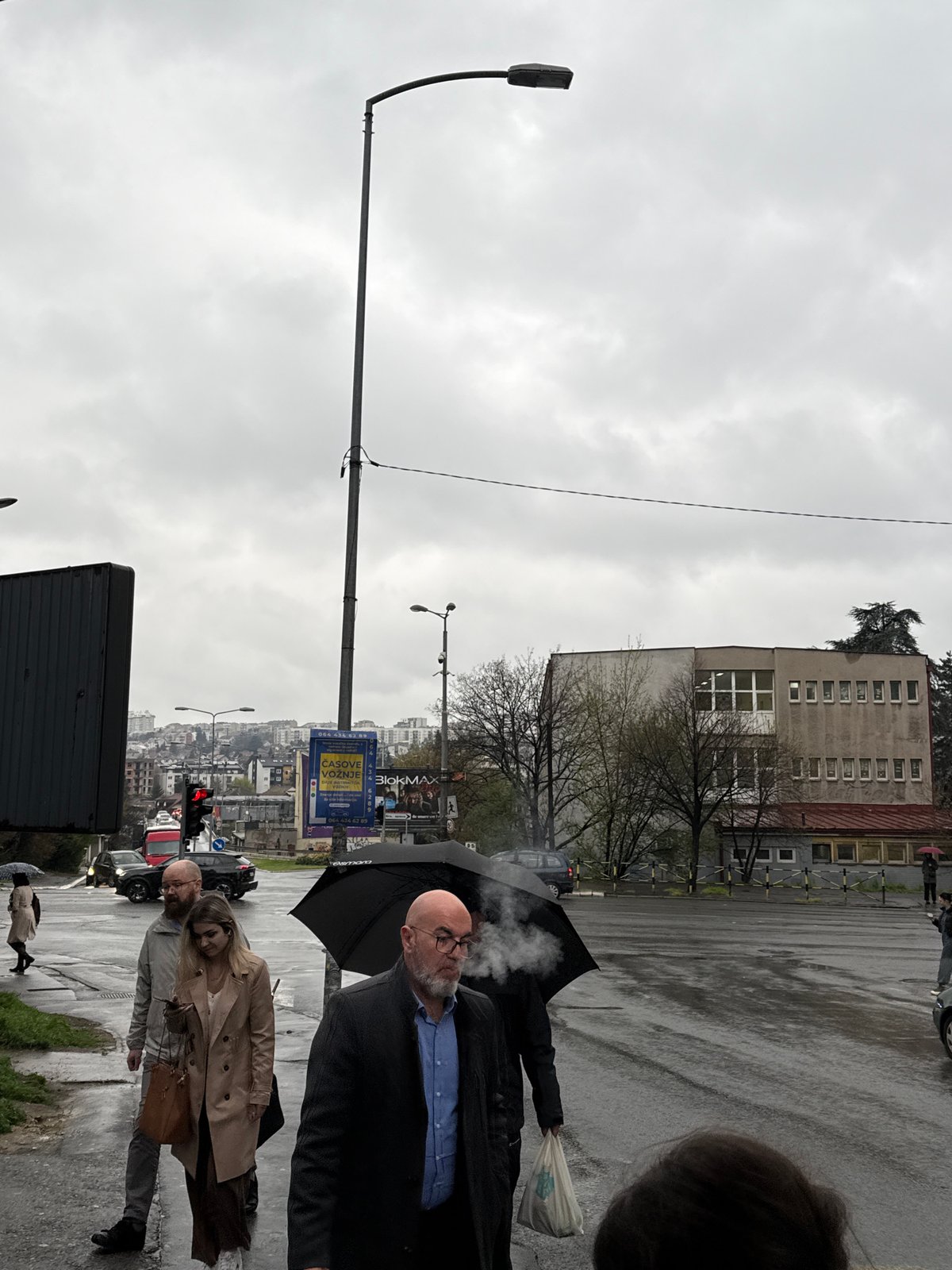 Pedestrians walk wet streets after rain in Belgrade suburb