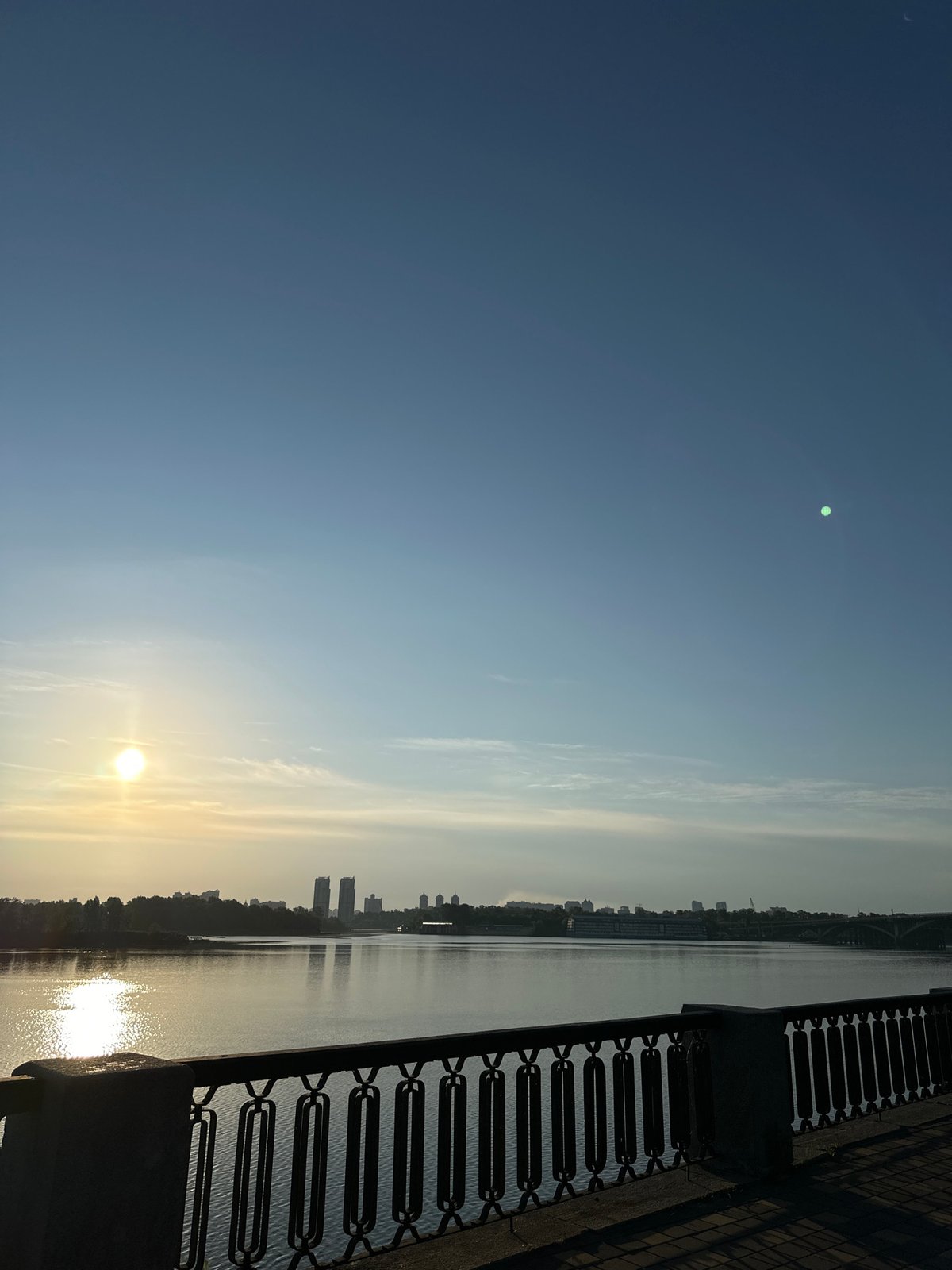 Sunrise along the Kyiv waterfront, ornate railing in frame